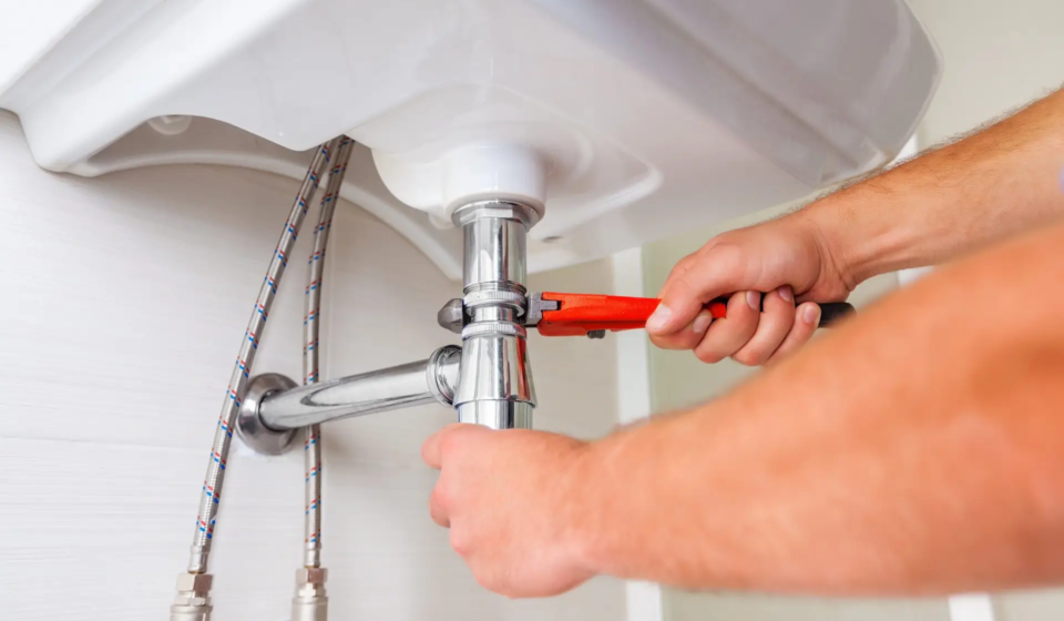 Hands of Professional plumber fixing pipes. Plumbing repair service.