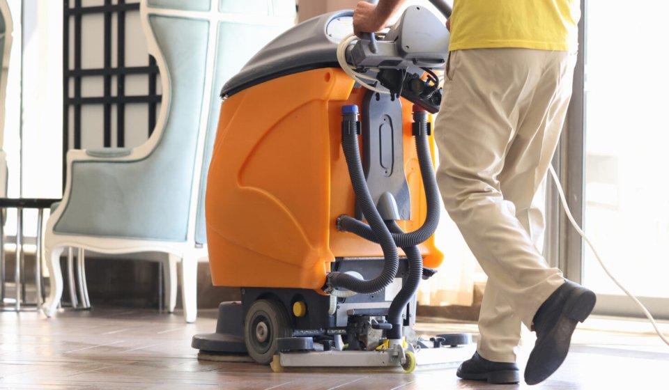 Janitor is cleaning hall with washing vacuum cleaner closeup