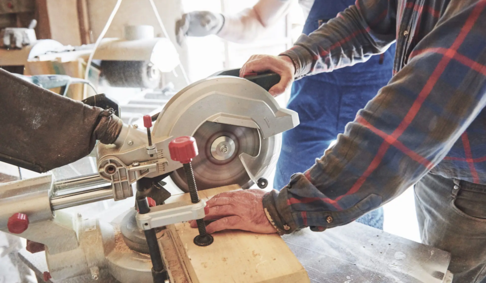 Master in a work suit using a grinder on a sawmill
