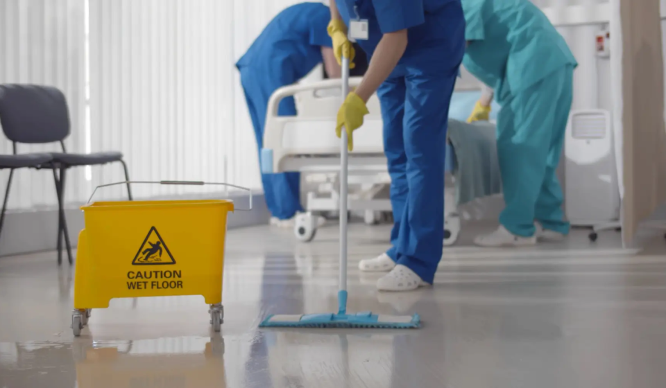 Nurses mopping floor and making bed in empty hospital ward. Medical staff in uniform wiping floor and cleaning intensive care unit in modern clinic